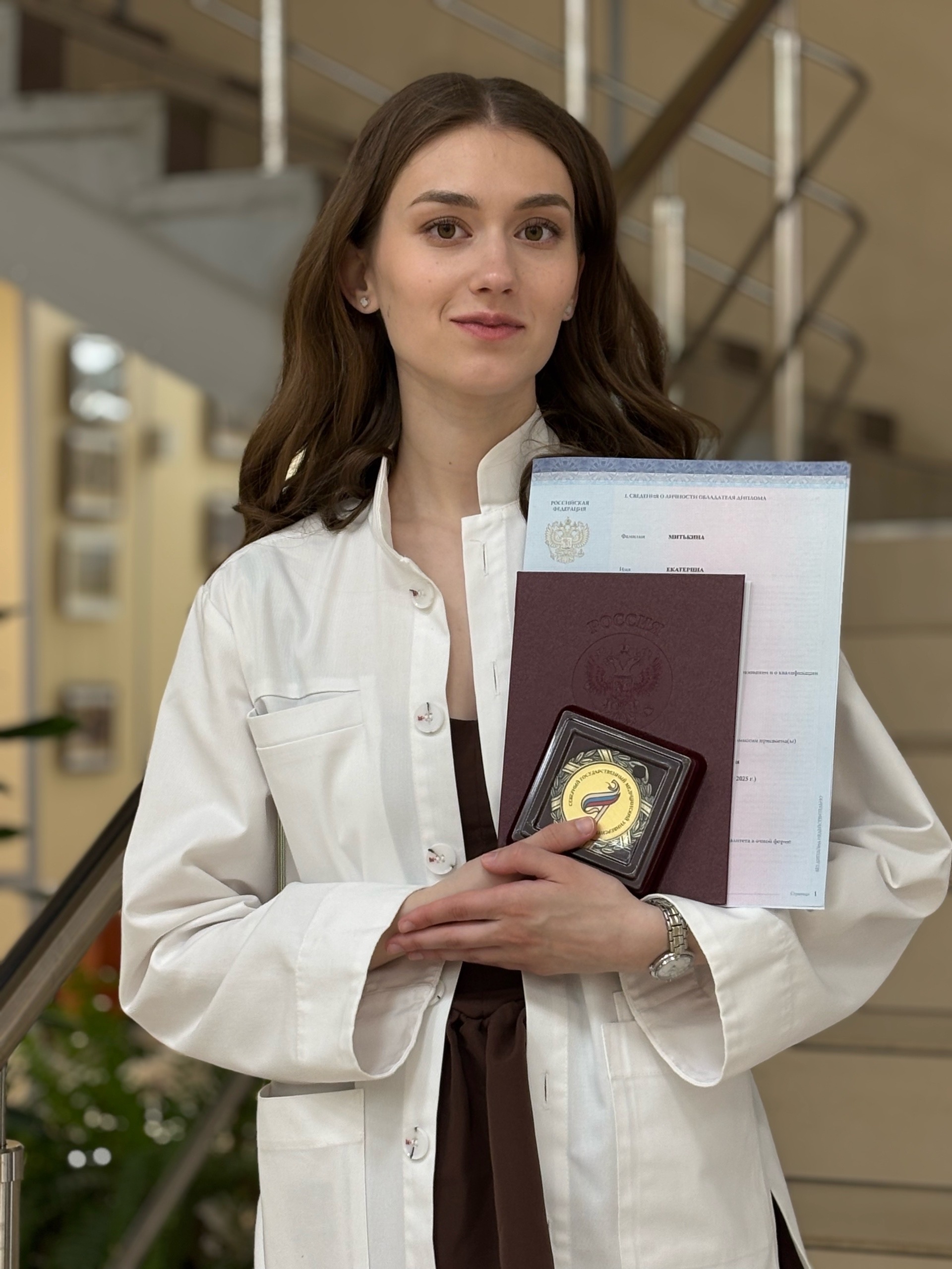 Ekaterina Mitkina holding her dental degree and distinction medal